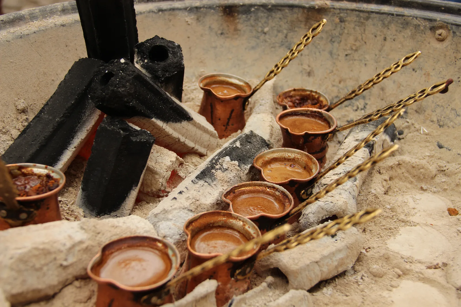 Mehrere Kupferkännchen mit Kaffee in Glut und Sand (Symbolbild)