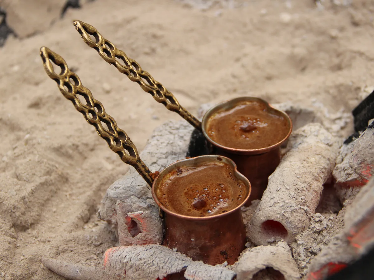 Zwei Kupferkännchen mit Mokka im heißen Sand (Symbolbild)